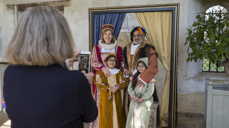 A family of four poses for a photograph dressed in Tudor outfits in the Orangery at Knole, Kent